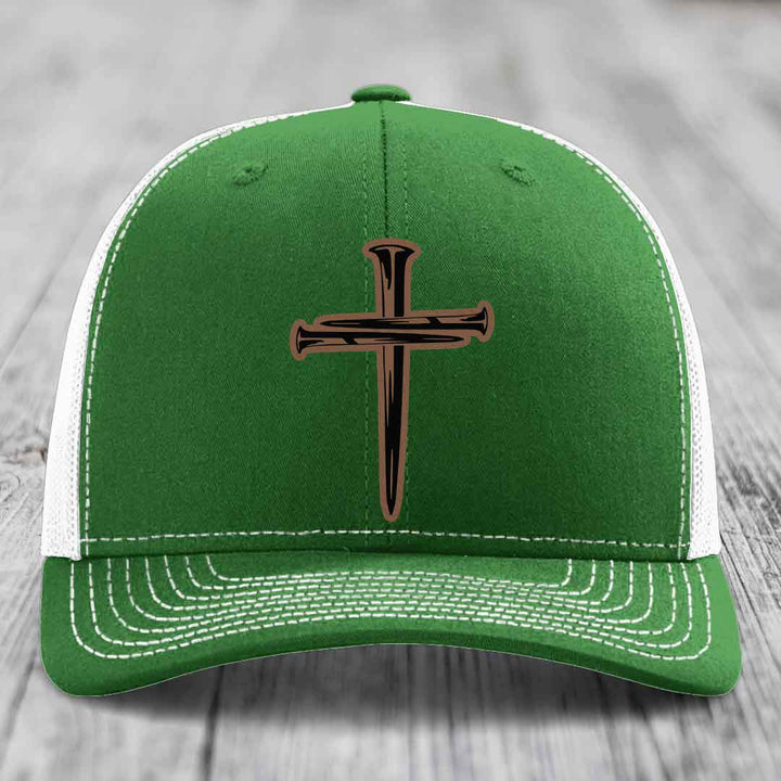 Beige trucker hat with black mesh back and a cross made of nails patch on front.