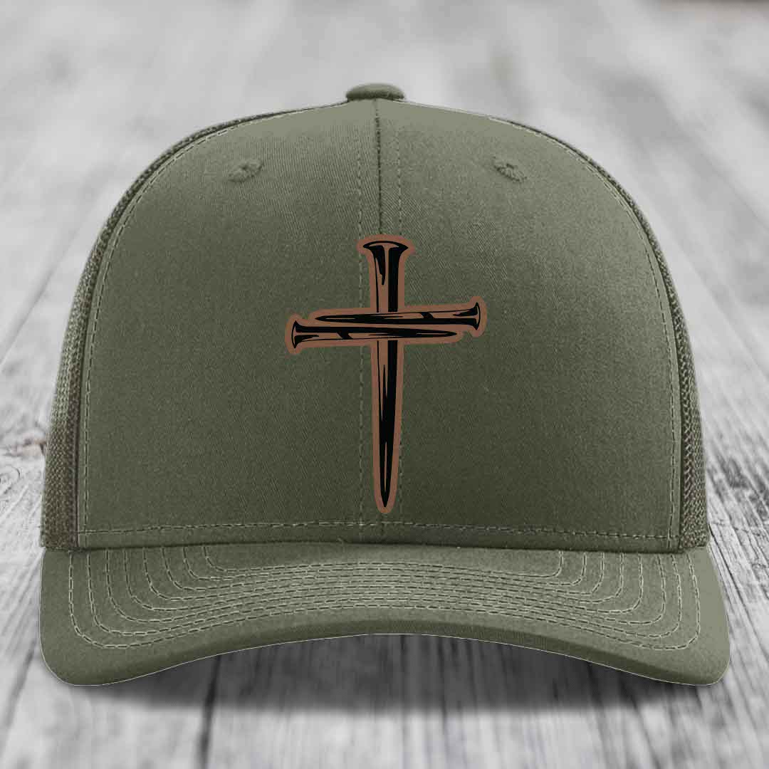 Olive green trucker hat with a cross made of nails patch on front.