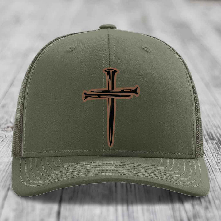 Olive green trucker hat with a cross made of nails patch on front.