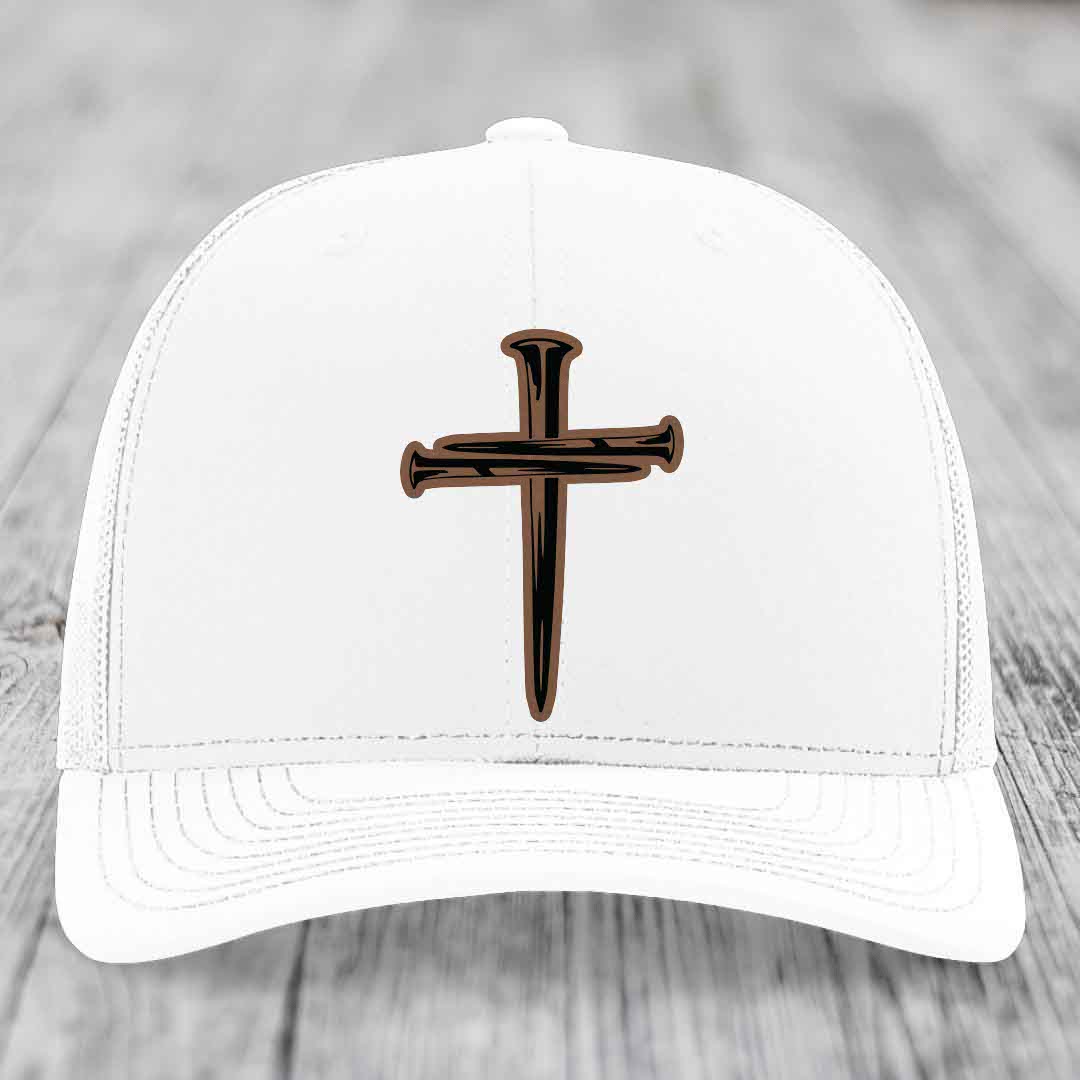 Camouflage trucker hat with a cross made of nails patch in tan and black.