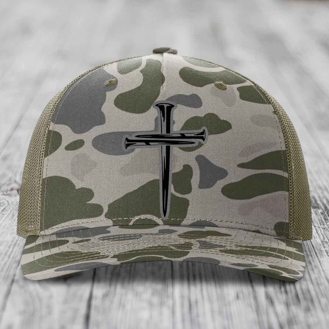 Camouflage trucker hat with black cross of nails patch on front.