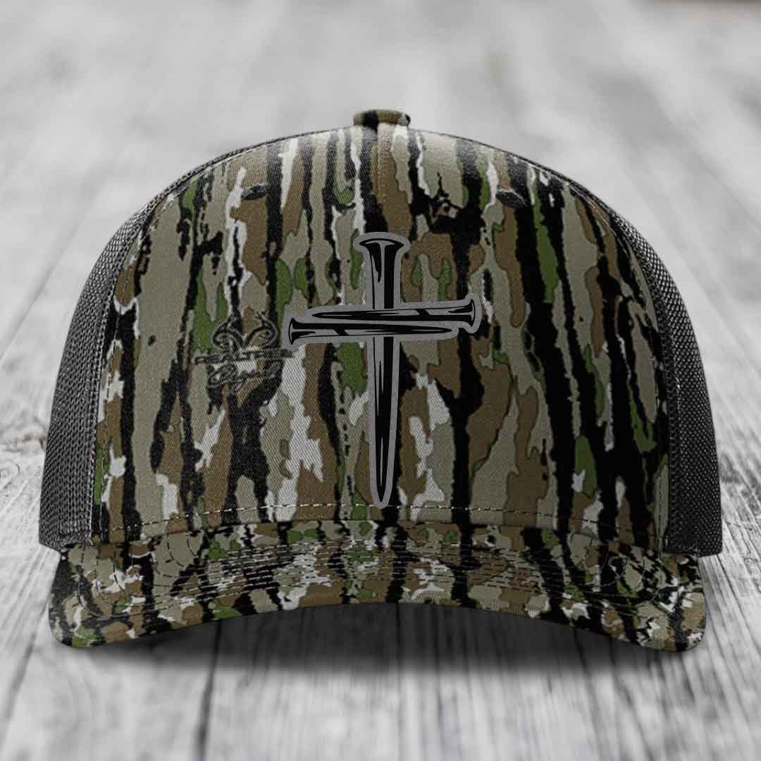 Black camouflage trucker hat with a silver cross of nails patch on front.