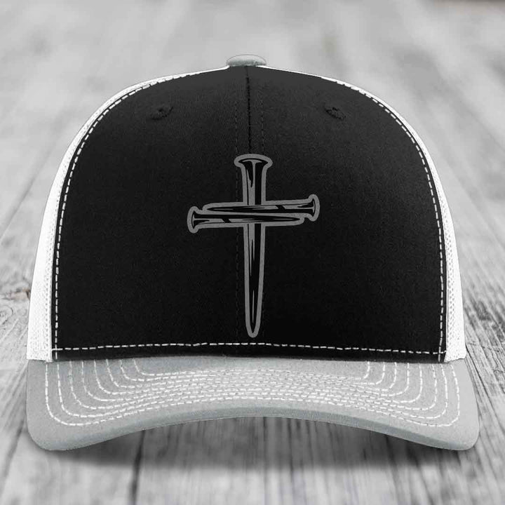 Brown trucker hat with white stitching and a cross made of nails patch on front.