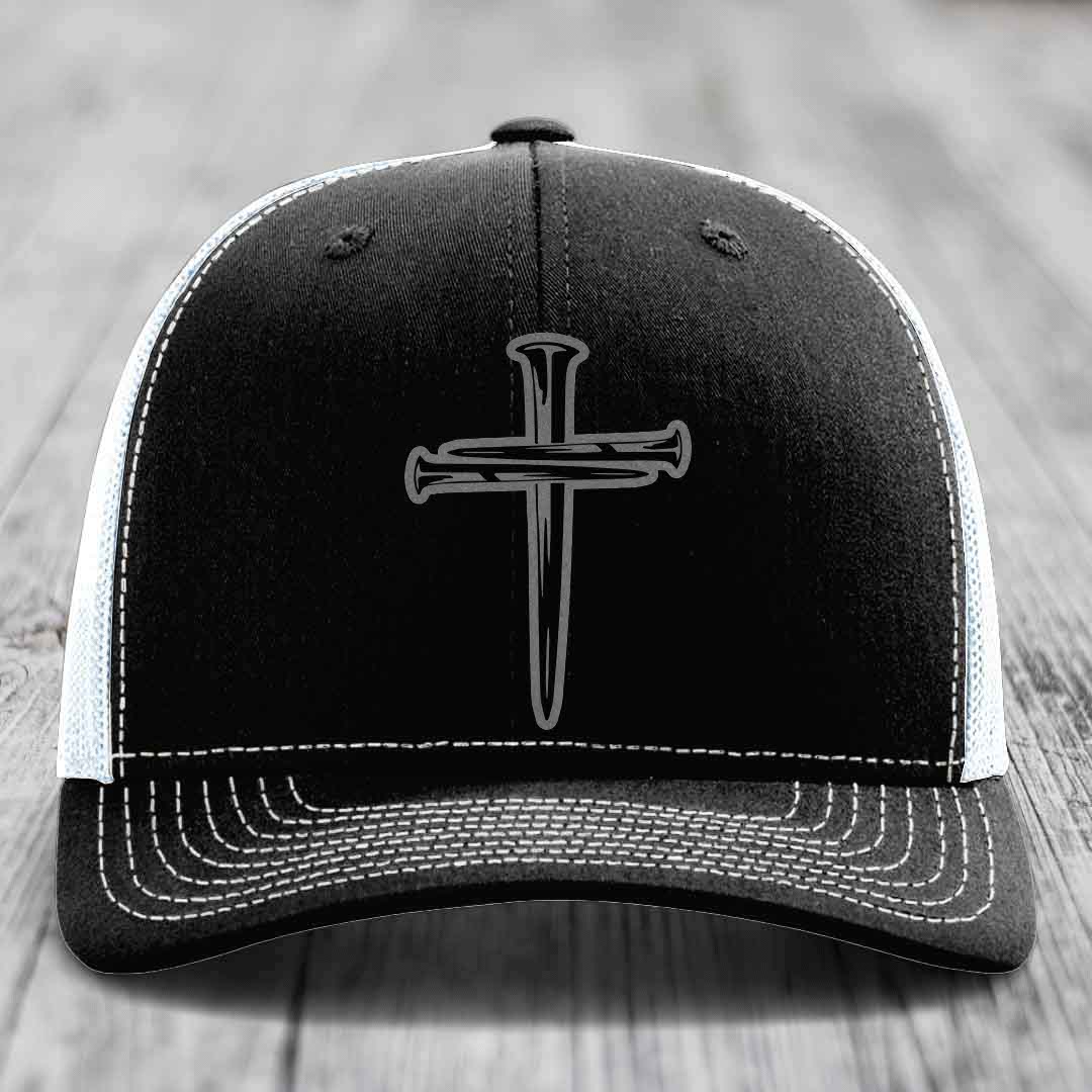 Black and grey trucker hat with a cross made of nails patch on front.