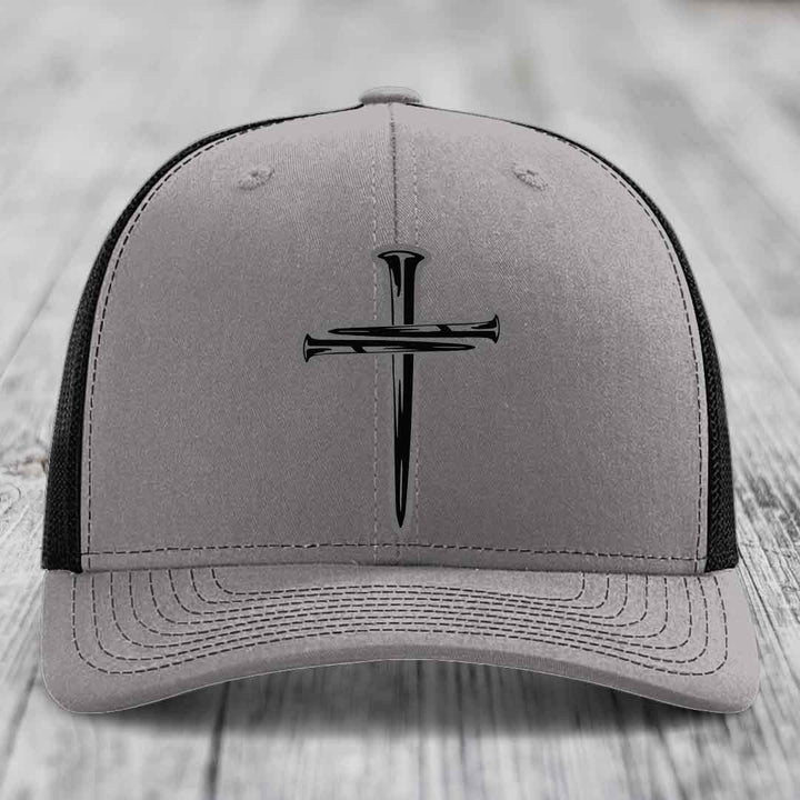 Grey trucker hat with black cross of nails patch and blue mesh sides.