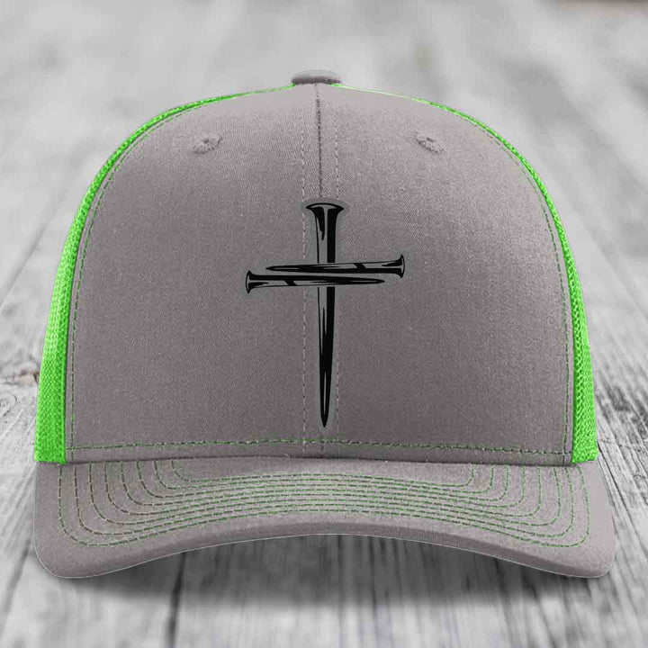 Grey trucker hat with orange mesh back and black cross of nails patch on front.