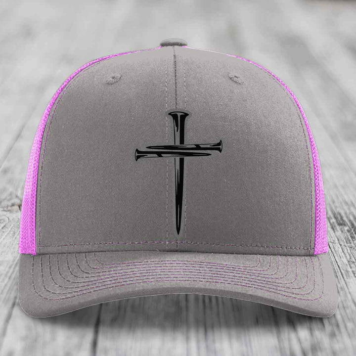 Grey trucker hat with black cross of nails patch and yellow mesh sides.