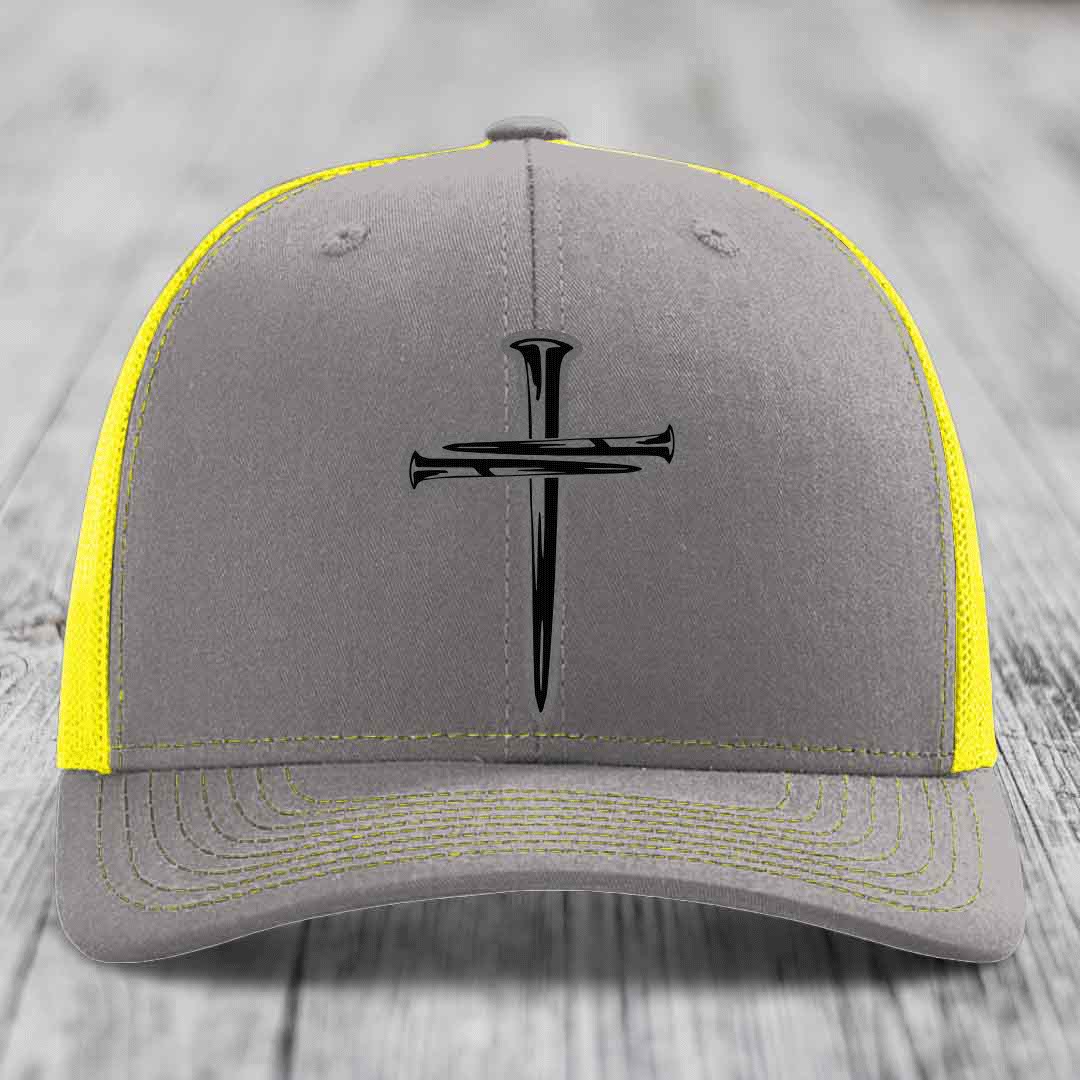 Brown trucker hat with black cross of nails patch on front, beige mesh back.