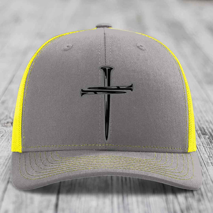 Brown trucker hat with black cross of nails patch on front, beige mesh back.