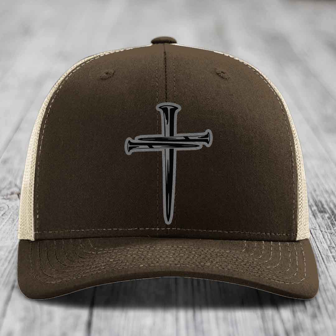 Dark green trucker hat with a cross made of nails patch on front.