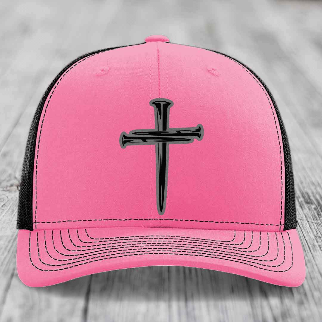 Green trucker hat with black cross of nails patch and white stitching.