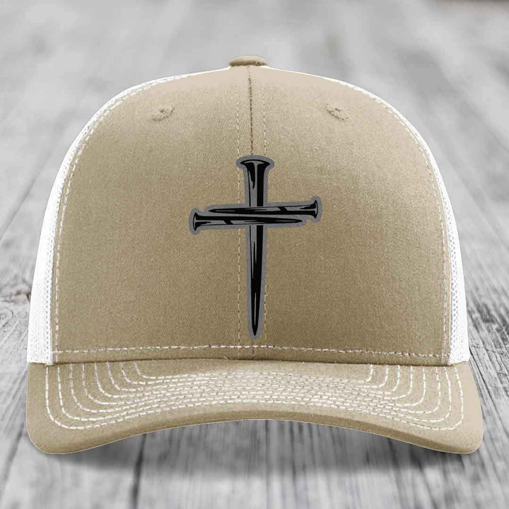Olive green trucker hat with a black cross of nails patch on front.