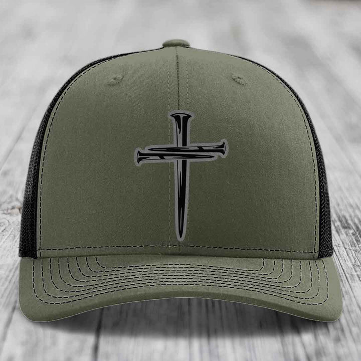 Black trucker hat with a silver cross made of nails embroidered on the front.