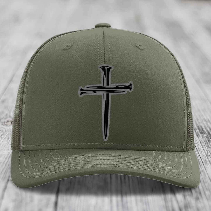 Olive green trucker hat with black cross of nails patch on front.