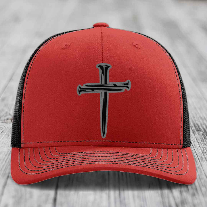 Blue trucker hat with black cross of nails patch on front.