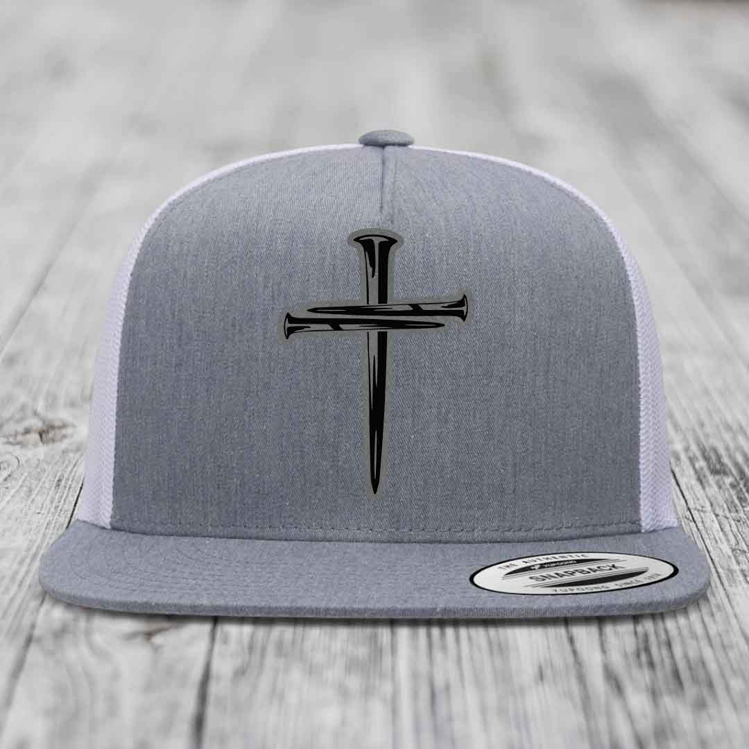 Grey and white trucker hat with black cross of nails patch on front.
