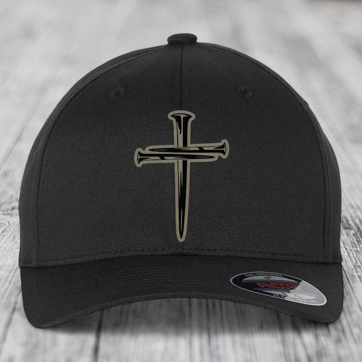Tan baseball cap with black cross of nails patch on front, Flexfit label visible.