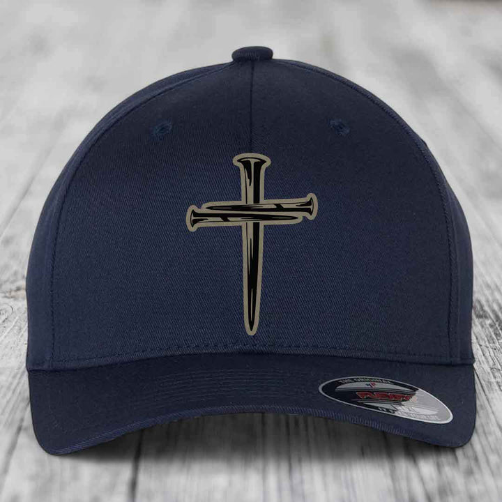 Red baseball cap with black cross of nails patch on front, displayed on wooden surface.