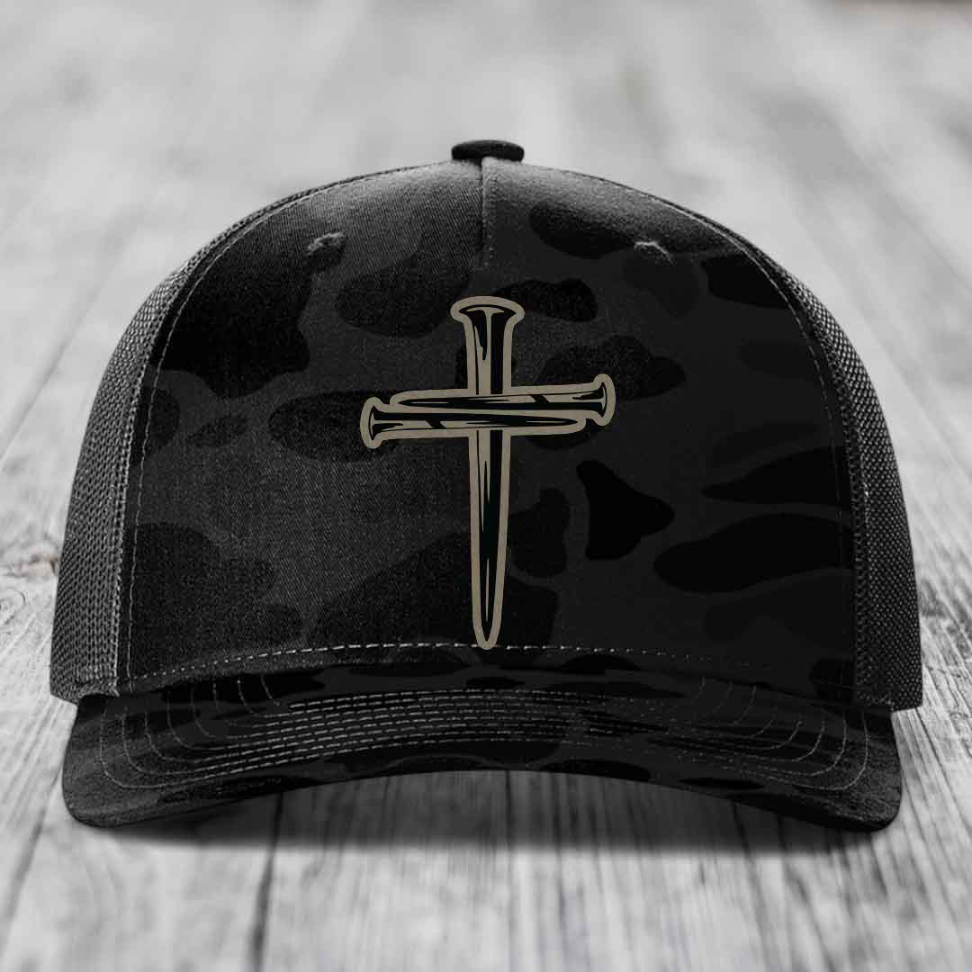 Camouflage trucker hat with black cross of nails patch on front.