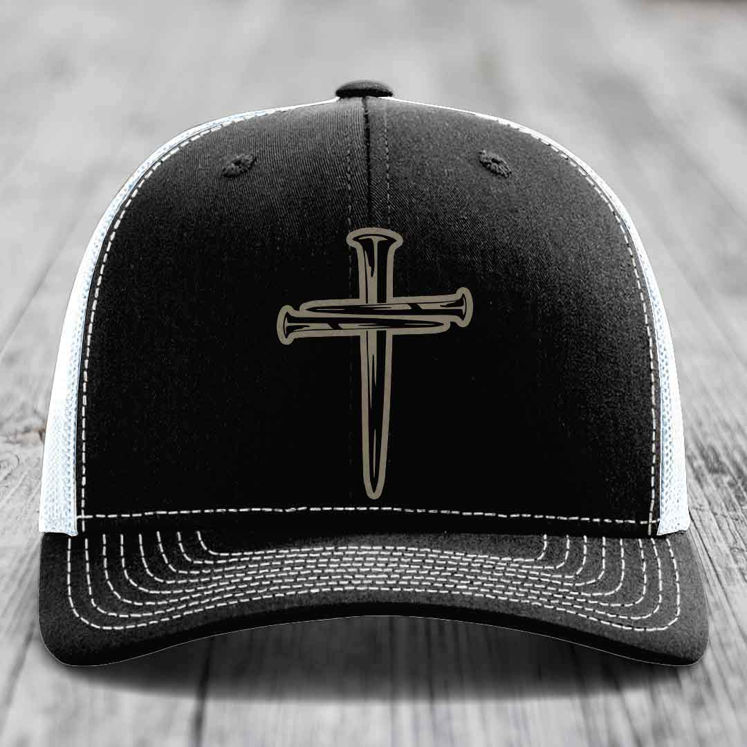 Black trucker hat with silver cross of nails patch on front, white mesh back and gray brim.