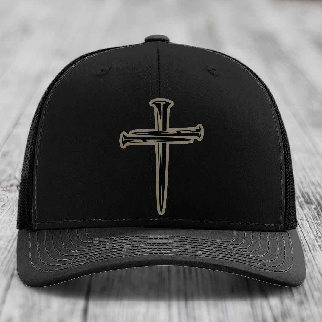 Tan trucker hat with black cross of nails patch, blue mesh back and stitching.