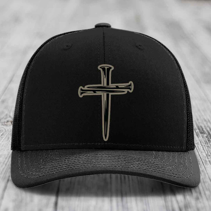 Tan trucker hat with black cross of nails patch, blue mesh back and stitching.