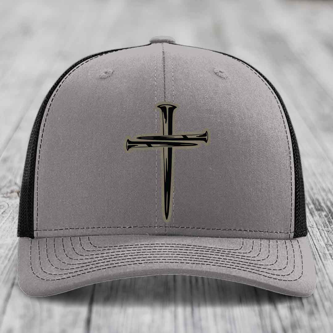 Grey trucker hat with blue mesh sides and a black cross of nails patch on front.