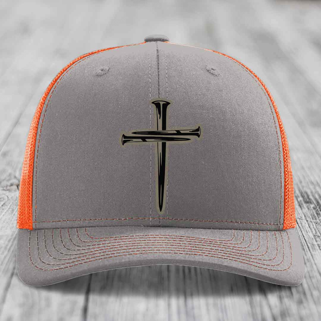 Grey trucker hat with black cross of nails patch and pink mesh sides.