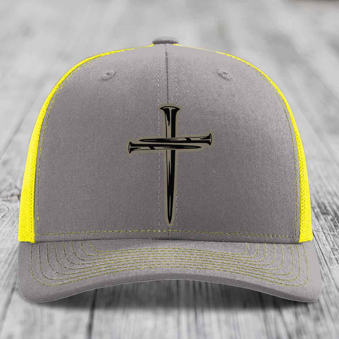 Brown trucker hat with black cross made of nails patch on front.
