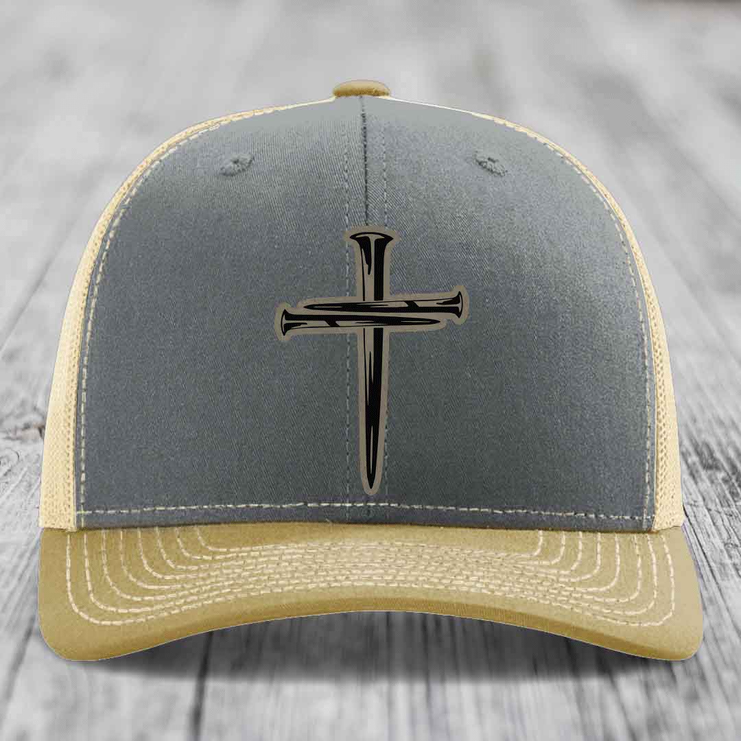 Grey trucker hat with black cross of nails leather patch on front.