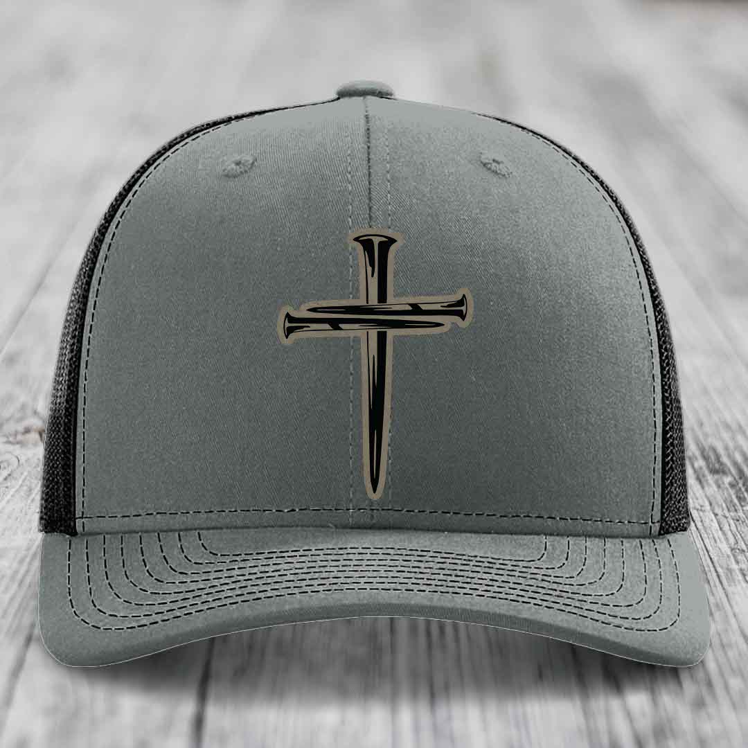 Grey trucker hat with black cross of nails patch on front, white mesh back and stitching.