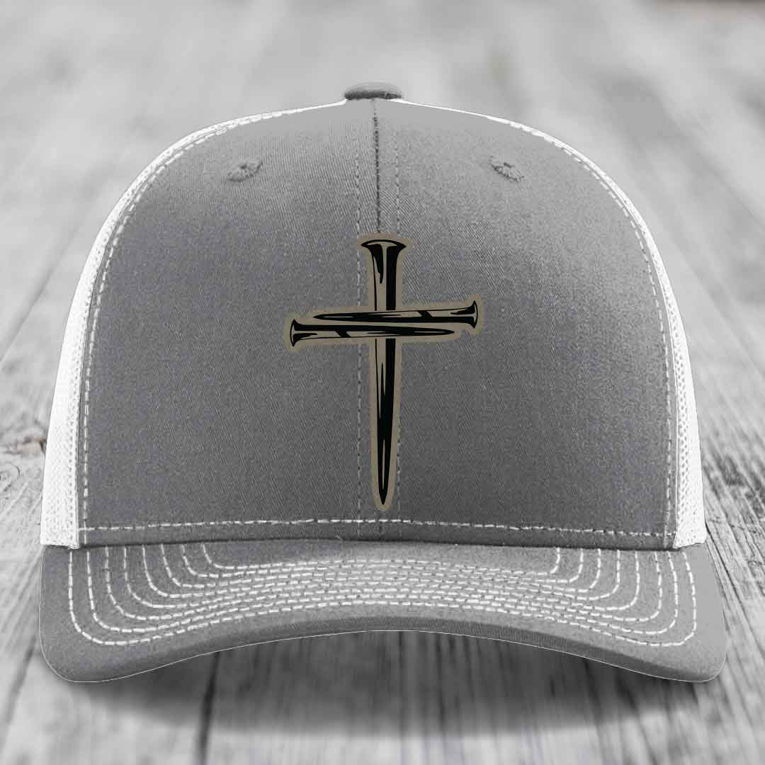 Pink trucker hat with black cross of nails patch on front, black mesh back.