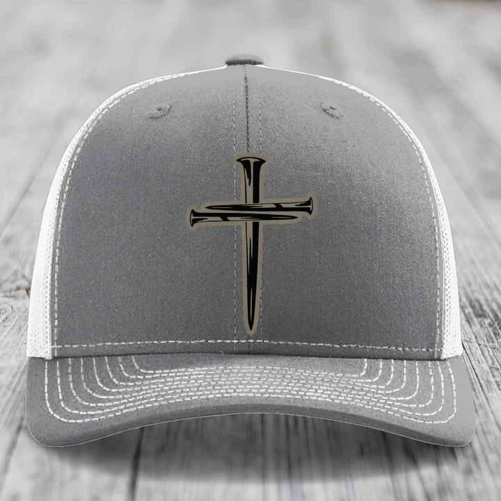 Pink trucker hat with black cross of nails patch on front, black mesh back.