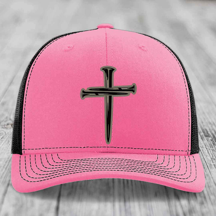 Green trucker hat with white mesh back and embroidered cross of nails patch.