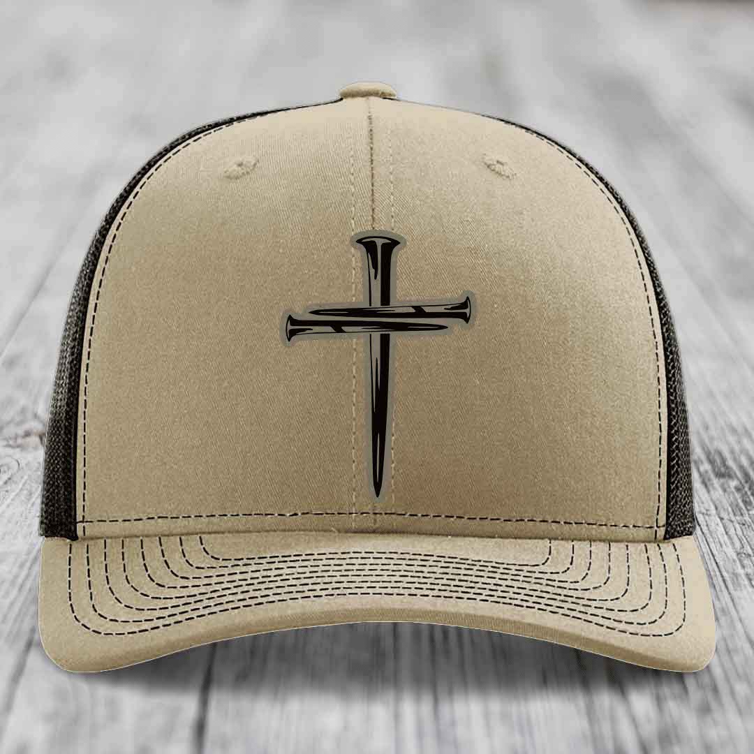 Tan trucker hat with black cross of nails patch on front, white mesh back and stitching.
