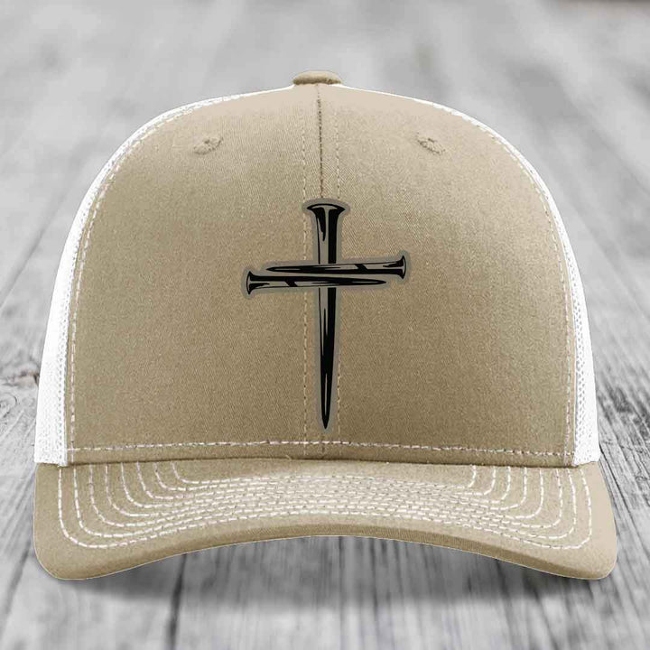 Olive green trucker hat with a cross made of nails patch on front.