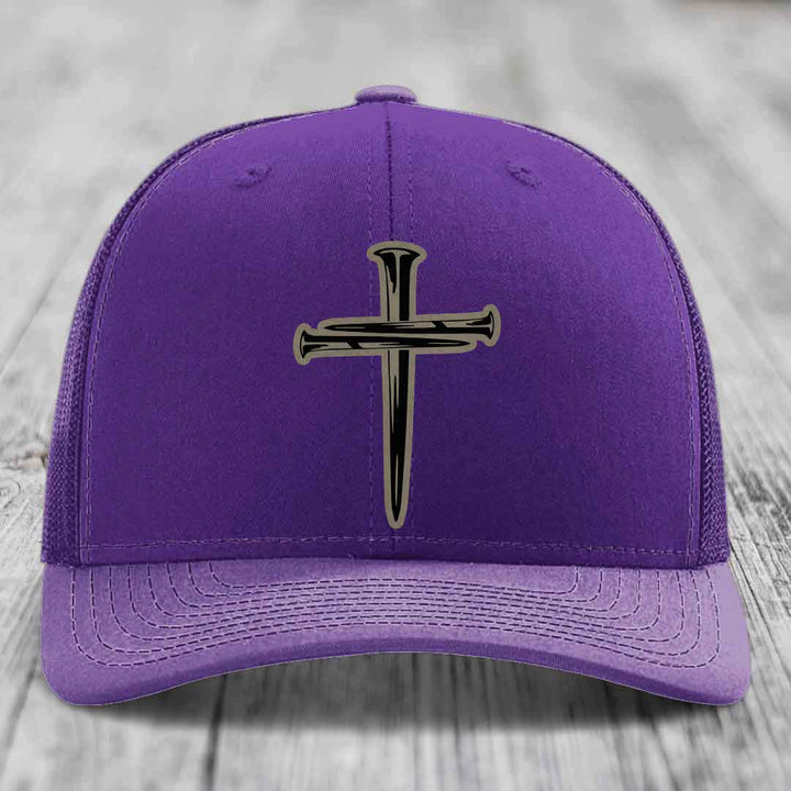 Red trucker hat with black mesh back and a cross of nails patch on front.