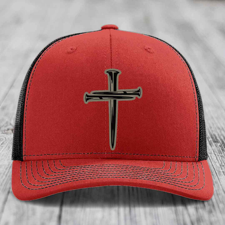 Blue trucker hat with black and tan cross of nails patch on front.