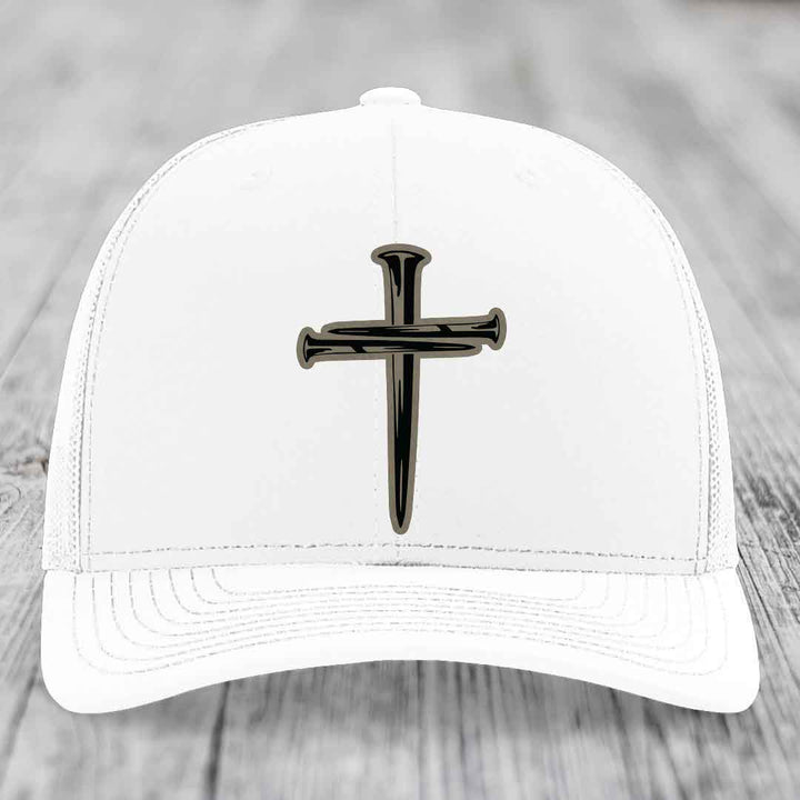 Black trucker hat with a brown cross made of nails patch on front.