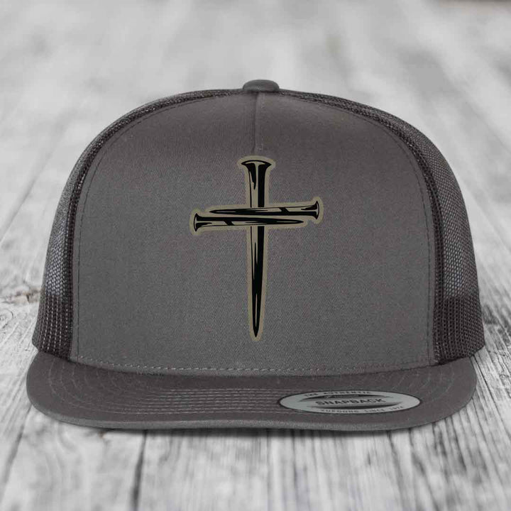 Grey trucker hat with black cross of nails patch on front, black mesh back, and Flexfit label.