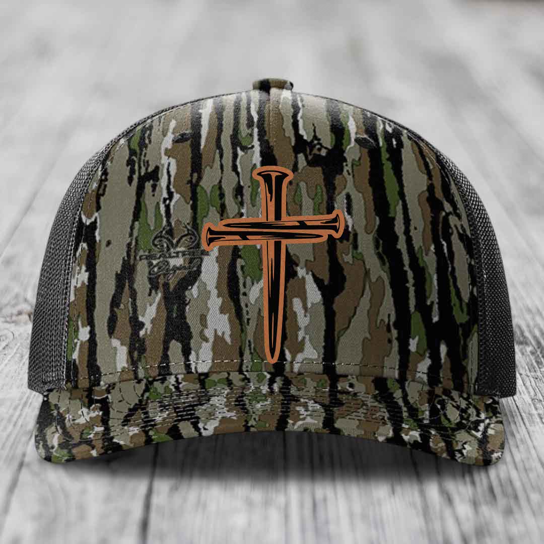 Black camouflage trucker hat with a brown cross of nails patch on front.