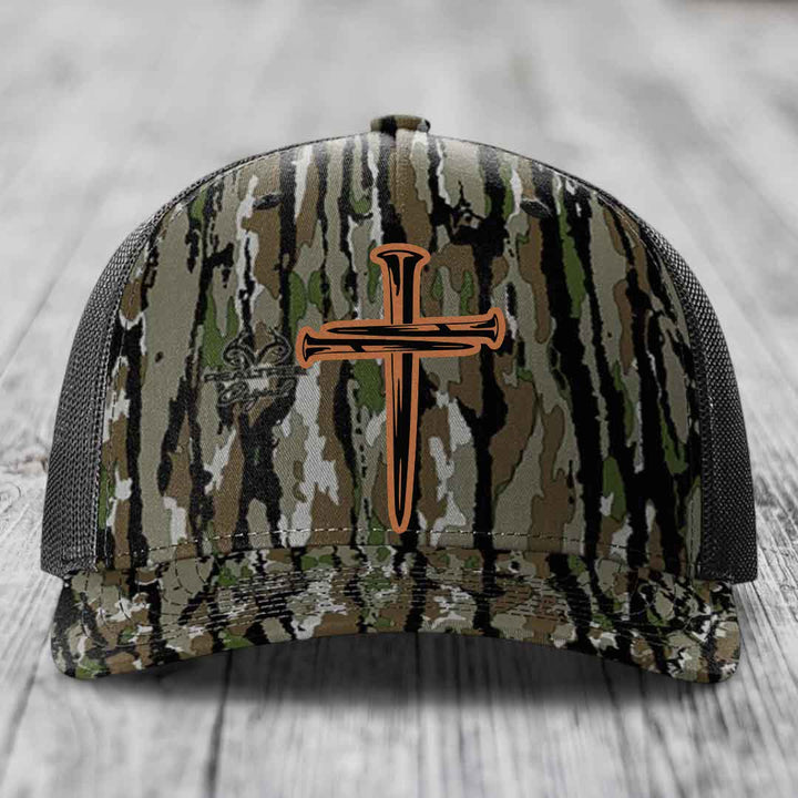 Black camouflage trucker hat with a brown cross of nails patch on front.