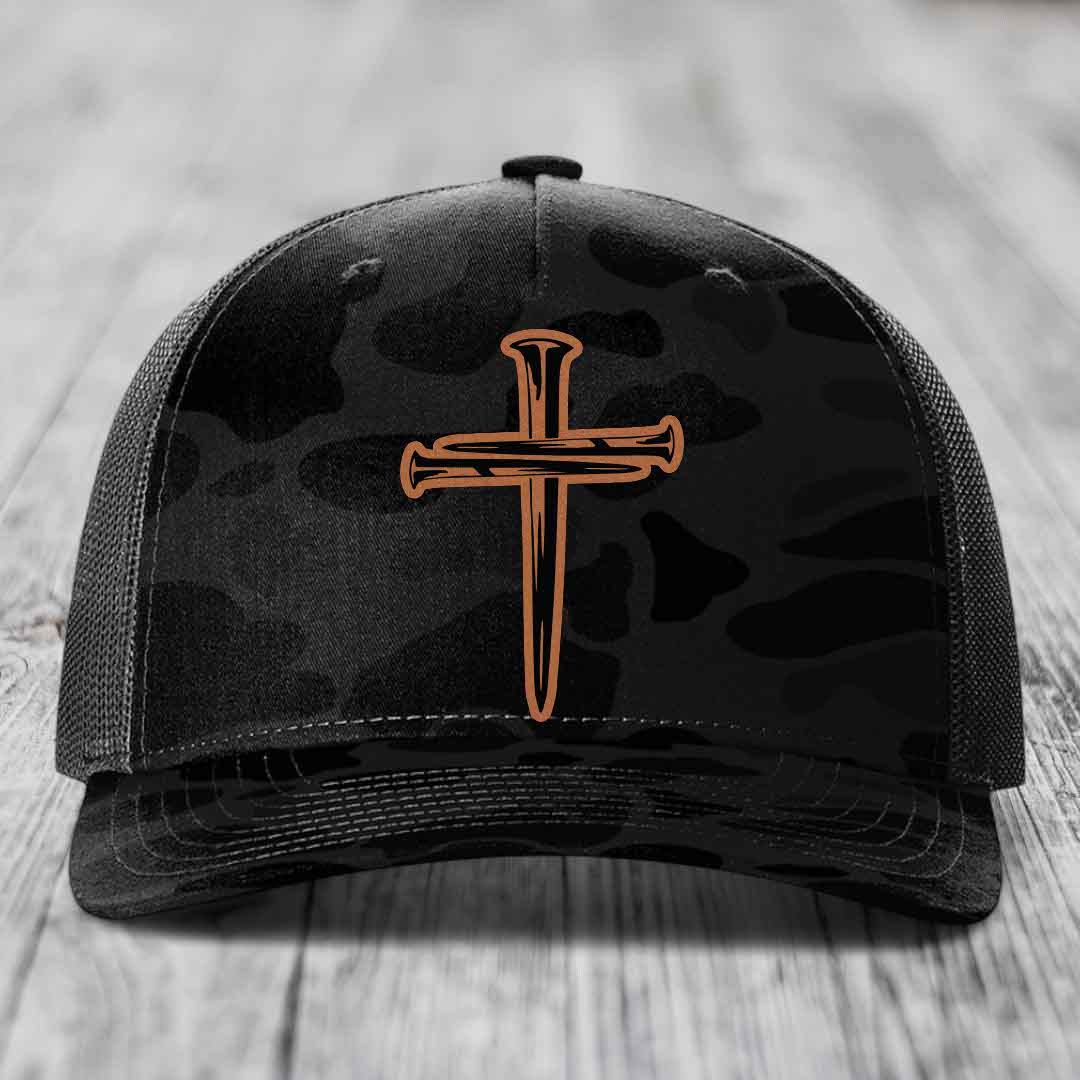 Camouflage trucker hat with a cross made of nails patch on front.