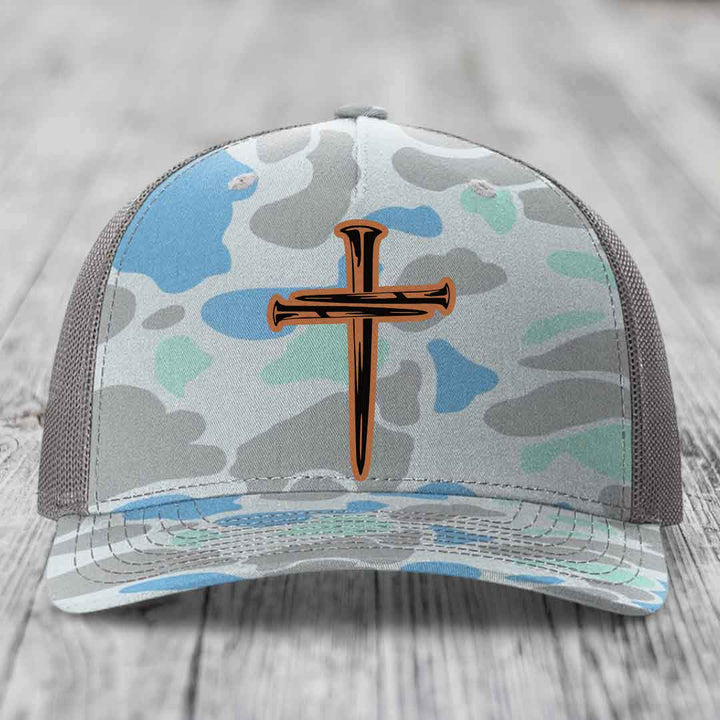 Camouflage trucker hat with a cross made of nails design on front.