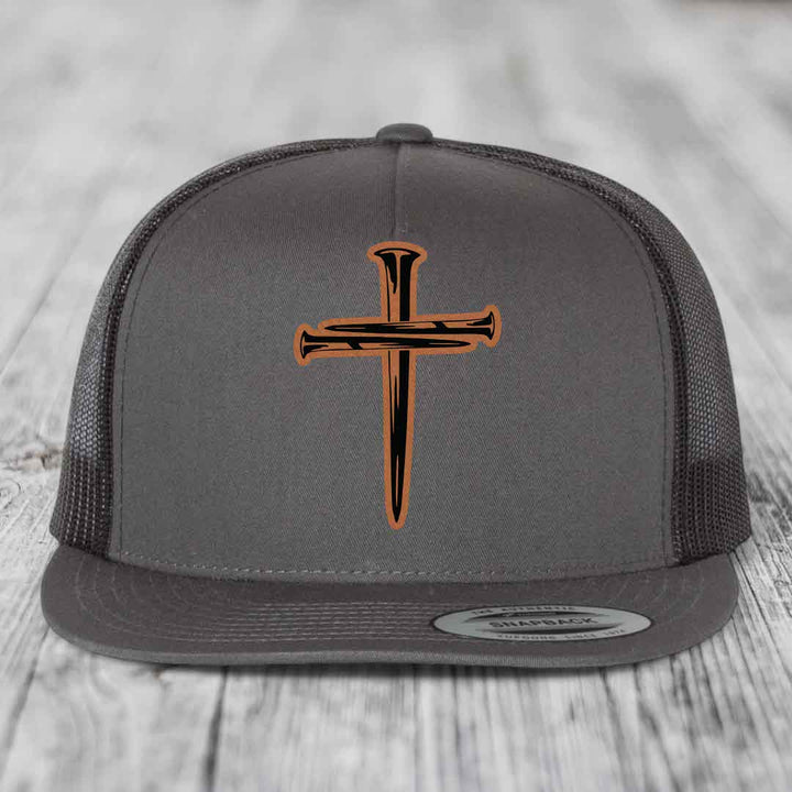 Grey trucker hat with black mesh back and orange cross of nails leather patch on front.