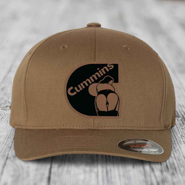 Dark brown Flexfit hat with Cummins logo patch featuring a stylized figure and text.