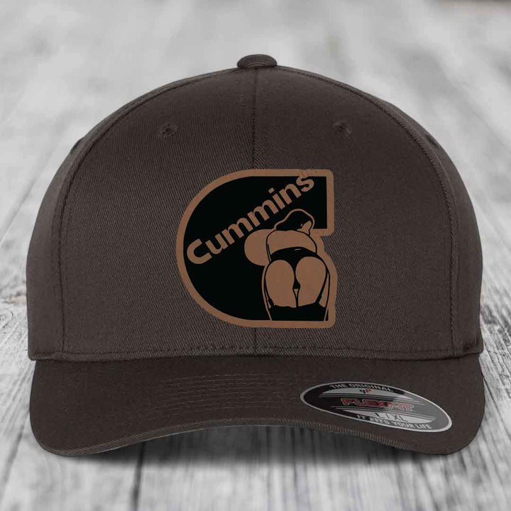 Dark brown Flexfit hat with Cummins logo patch featuring a stylized figure and text.