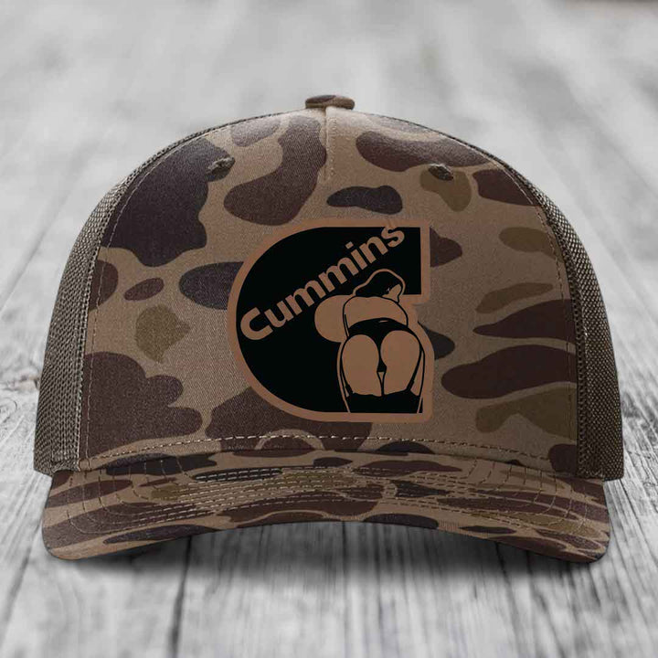 Camouflage trucker hat with Cummins logo patch featuring a stylized figure.