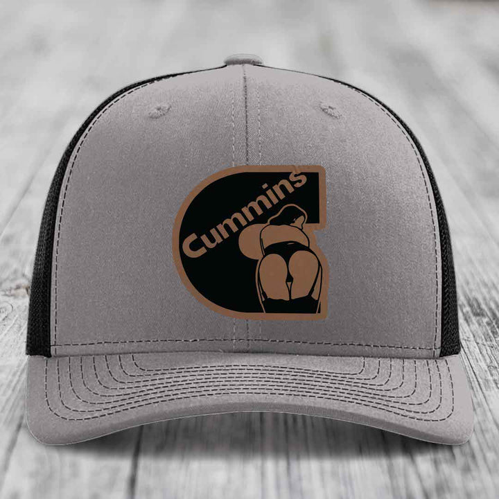 Grey trucker hat with blue mesh sides and a Cummins logo patch featuring a stylized &
