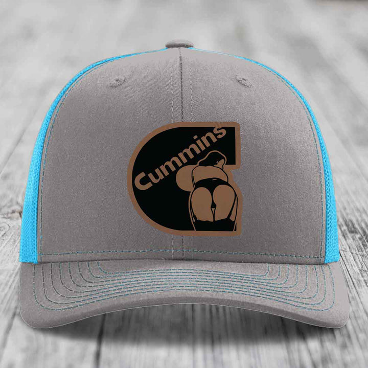 Grey trucker hat with neon green mesh and stitching, featuring a Cummins logo patch.